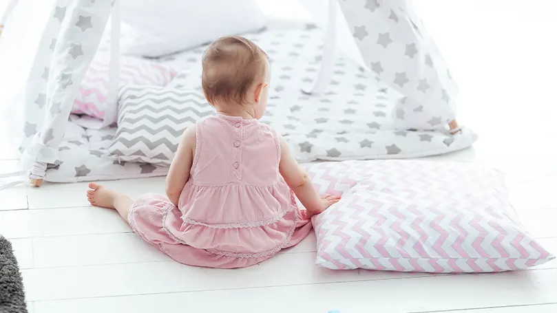 An image of a child sitting next to a bunch of toddler pillows