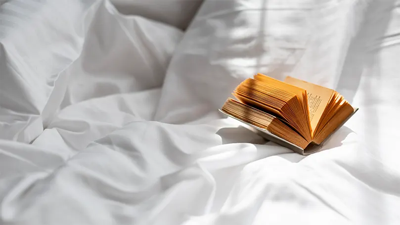 A book on bed sheets in bed