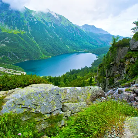 An image of a landscape with mountains and a lake in the distance