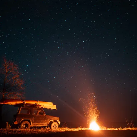 An image of a campfire next to a van at night