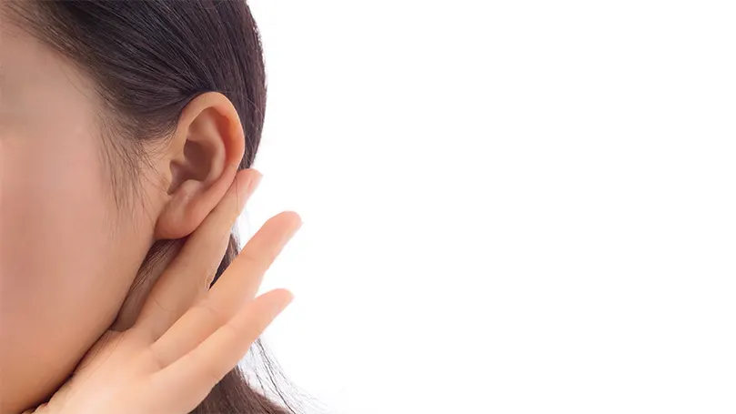 An image of a person with their hand to their ear listening to something