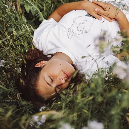An image of a woman sleeping outside in some grass
