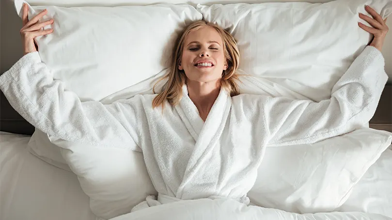 A woman in a bathrobe laying down in bed