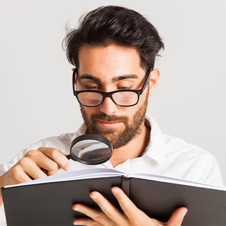 A man with glasses looking in the book