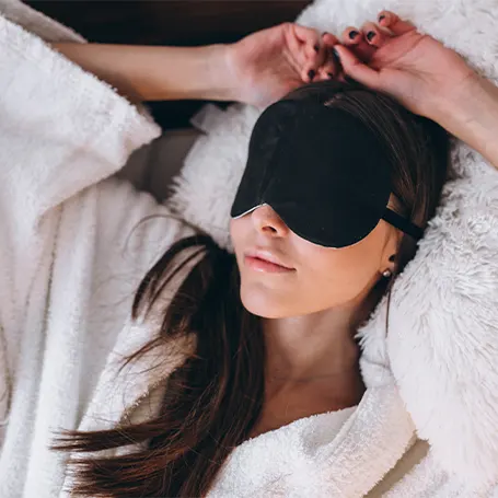 An image of a woman with a sleep mask sleeping on her back