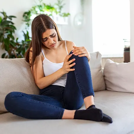 An image of a woman with leg pain holding her knee