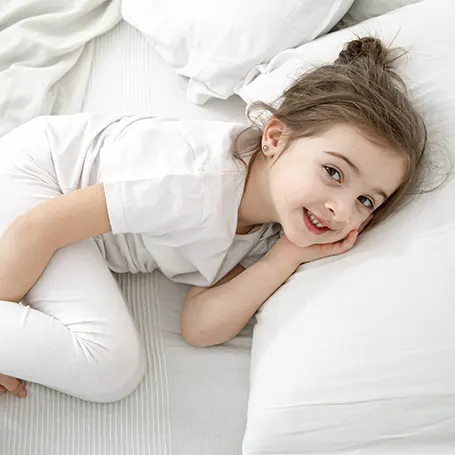 An image of a little girl resting on a big pillow
