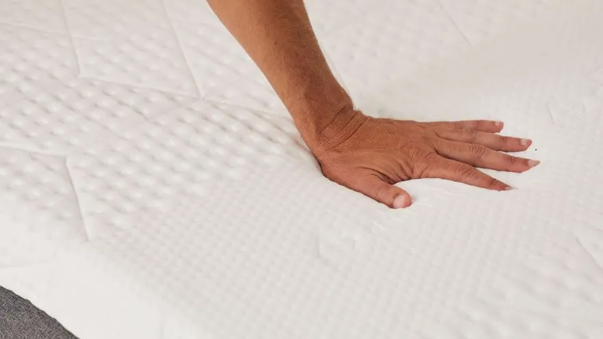 A hand touching the comfort cover of the Emma Original Plus Mattress