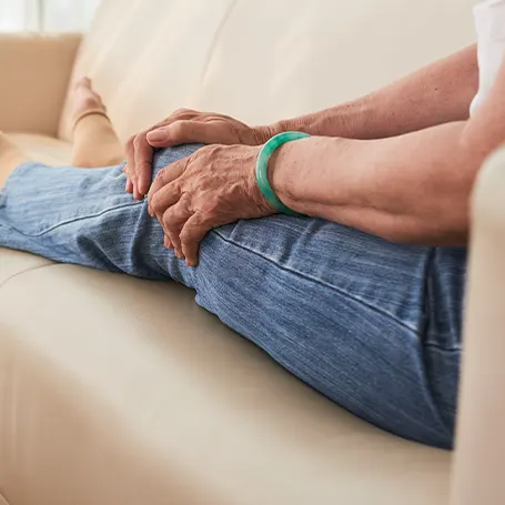 An image of an elederly woman touching her knee