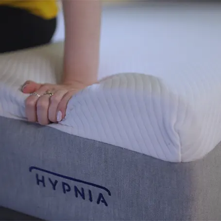 Hand pressing down on the edge of the mattress.