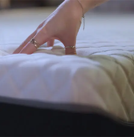 Hand pressing down on the mattress surface.