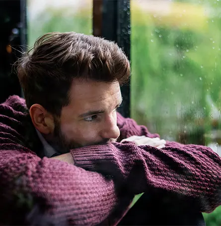 An image of a man with SAD looking out a window