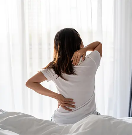 An image of a woman in bed suffering from back pain